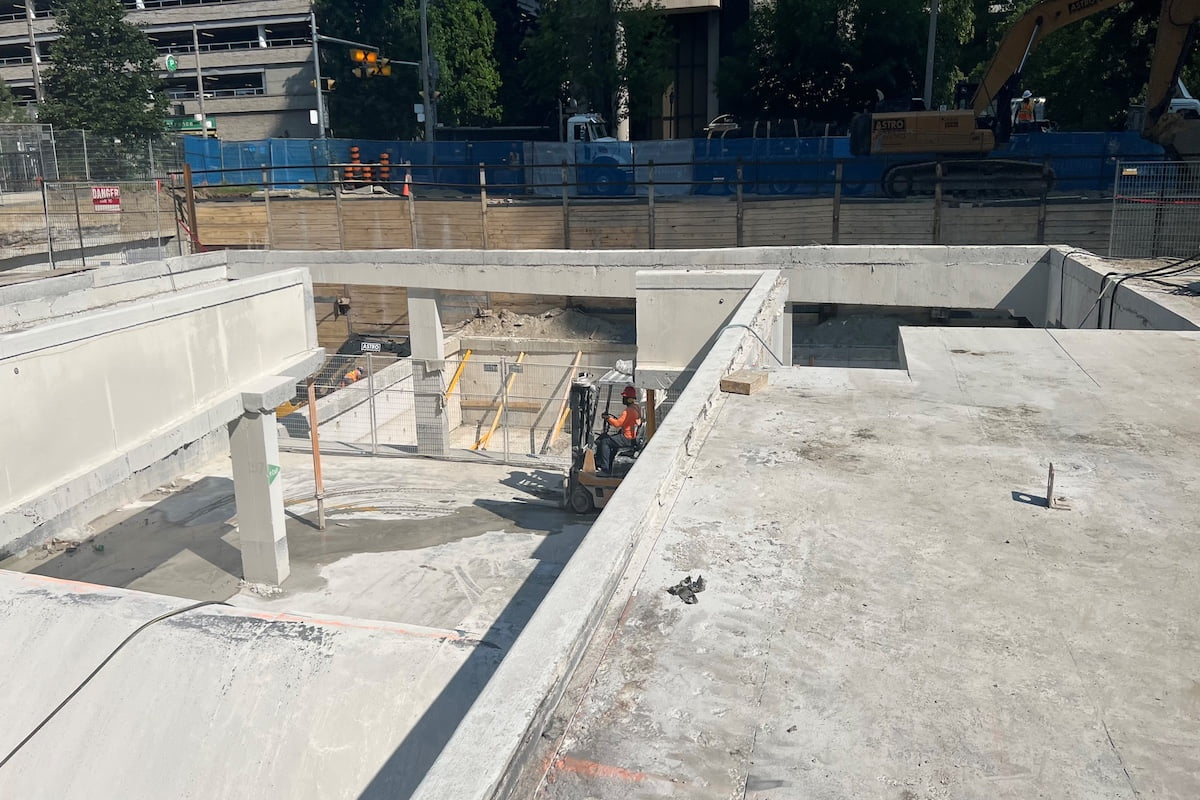 Blackcore Environmental - A construction worker operates a small vehicle in a partially built concrete structure at an urban building site.
