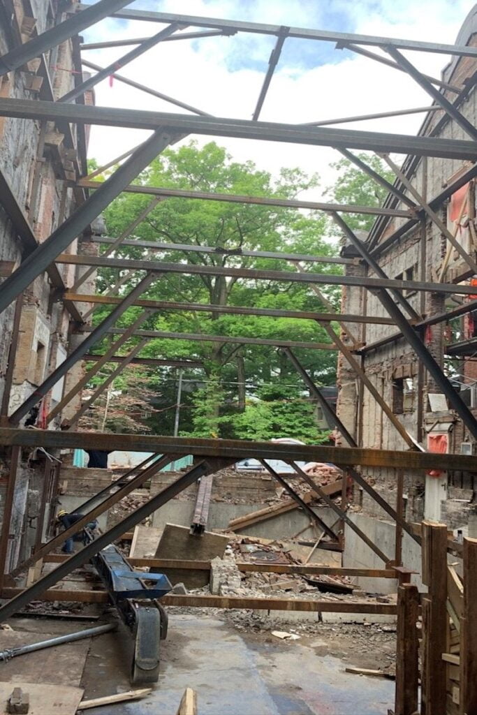 Blackcore Environmental - A partially demolished building with exposed steel beams and construction rubble, showing an open view of trees and sky in the background.
