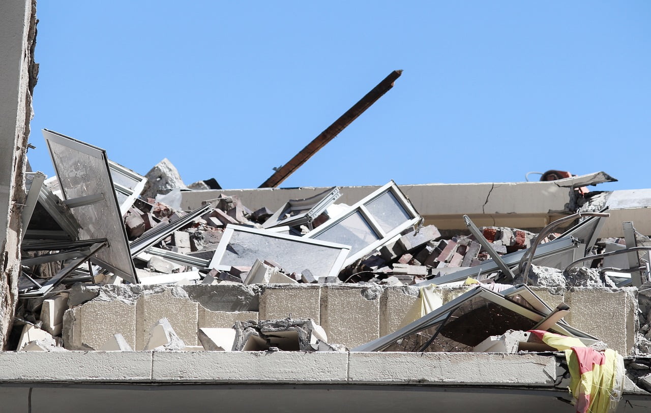 Blackcore Environmental - A partially collapsed building with broken windows and debris scattered, seen under a clear blue sky.