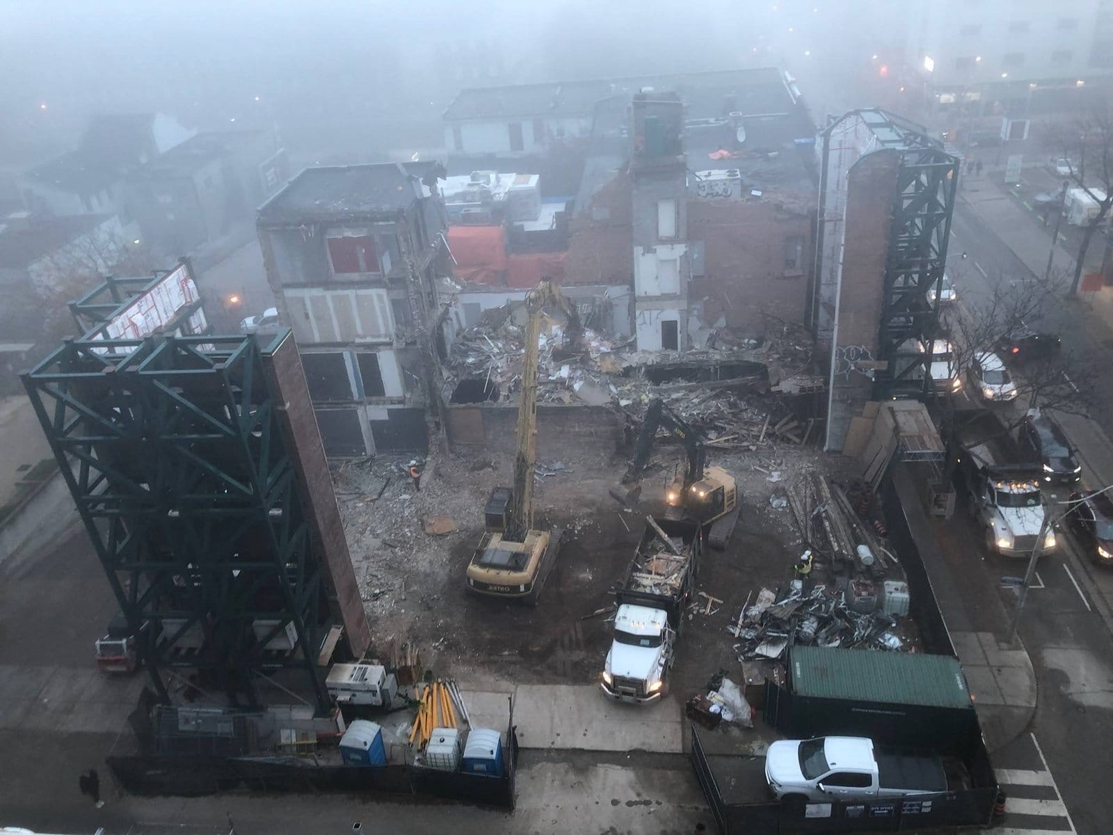 Blackcore Environmental - A demolition site with excavators and lorries clearing debris from a partially demolished building on a foggy day.