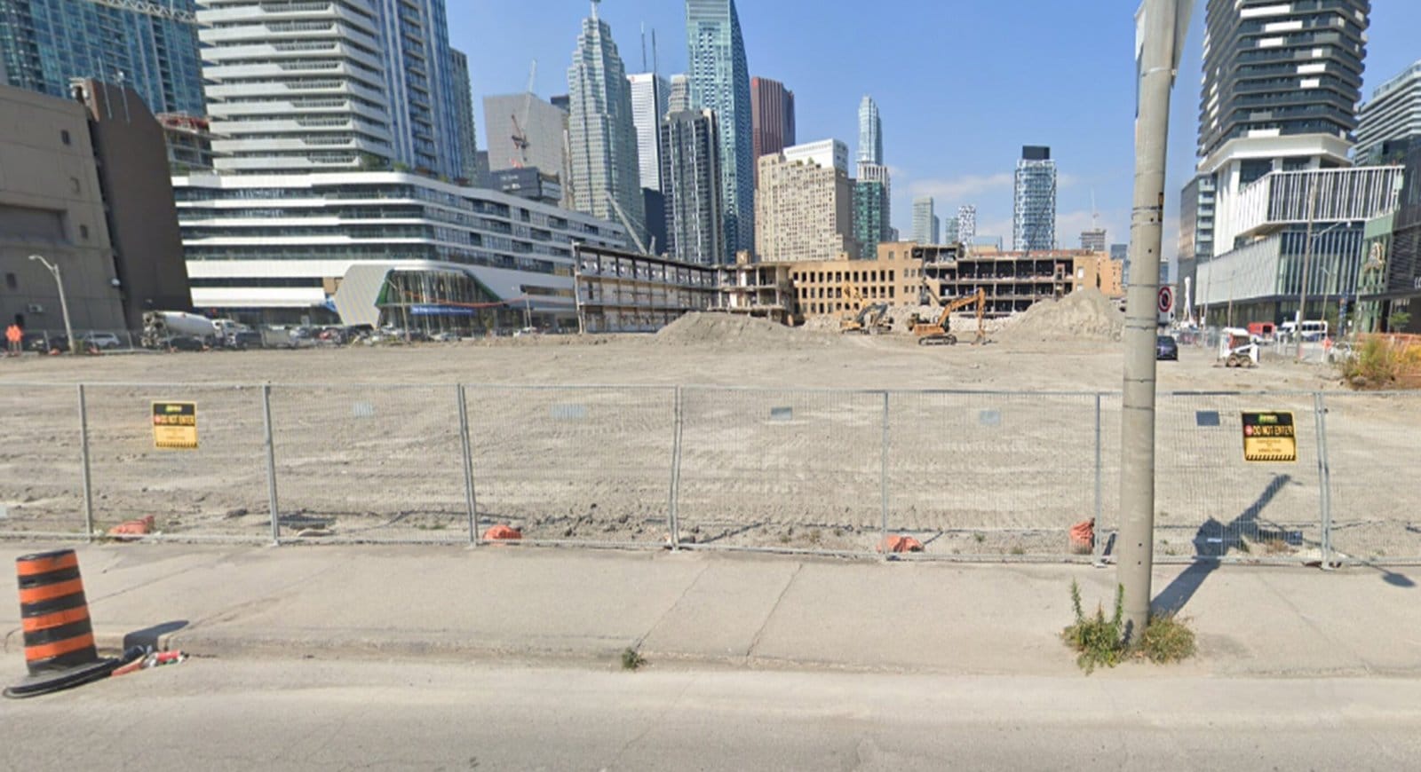 Blackcore Environmental - Construction site with a fenced-off empty dirt lot in an urban area, surrounded by high-rise buildings under a clear sky.