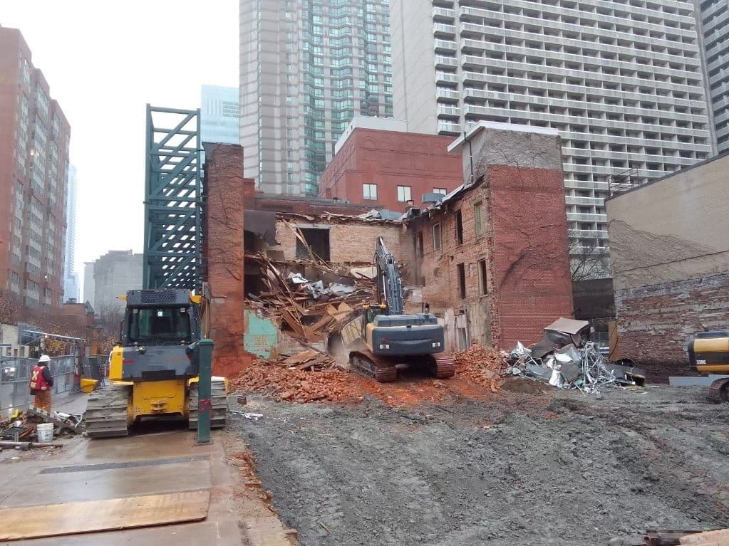 Blackcore Environmental - Excavators demolish a partially collapsed brick building in an urban area, with debris and construction equipment visible on the site.