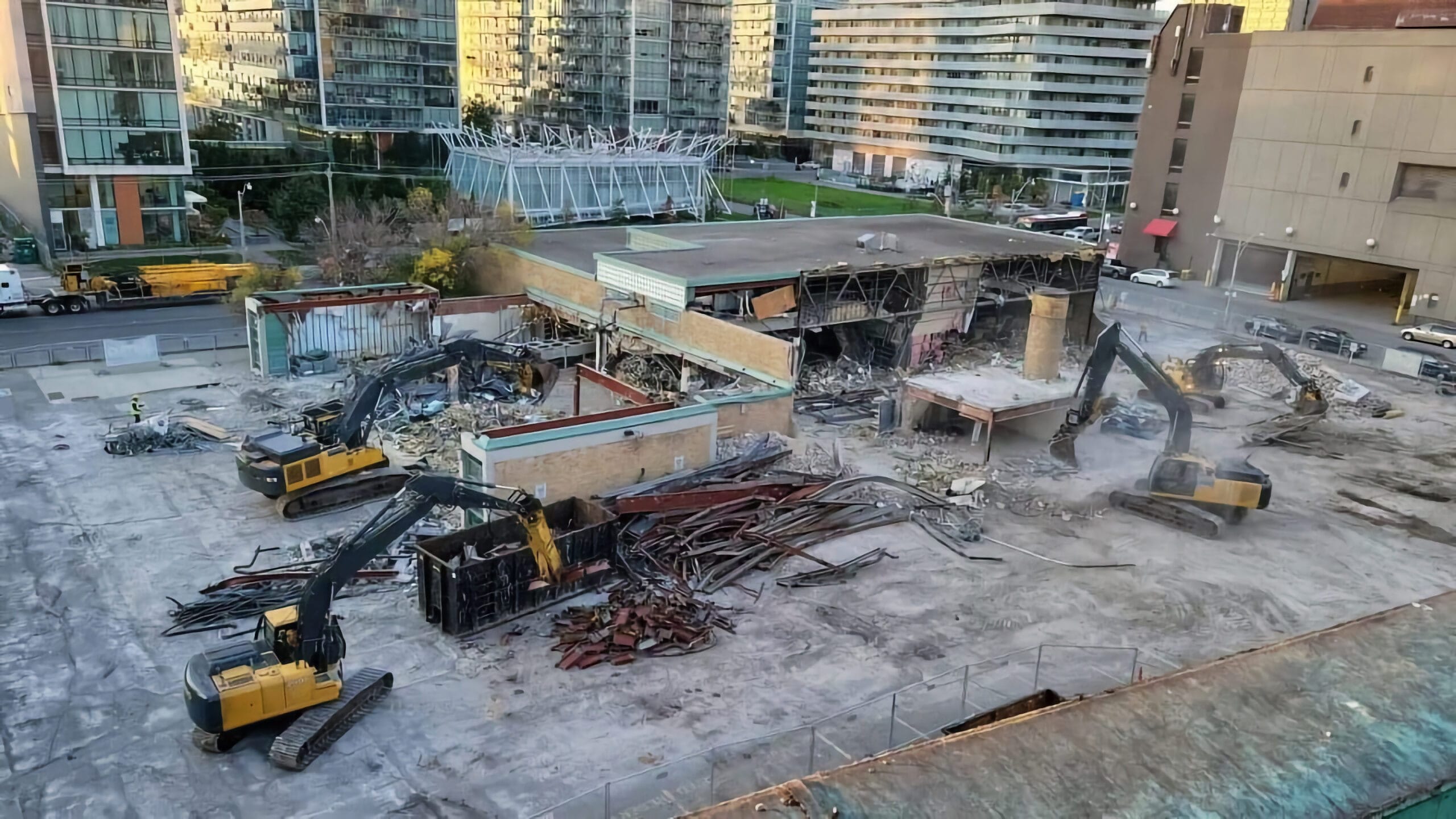 Blackcore Environmental - Two diggers demolish a large building on a construction site surrounded by tower blocks and scattered rubble.