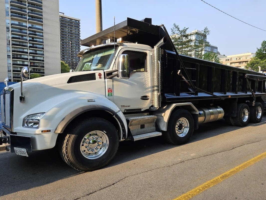 Blackcore Environmental - A white and black tipper lorry is parked on a city street with buildings and trees in the background.
